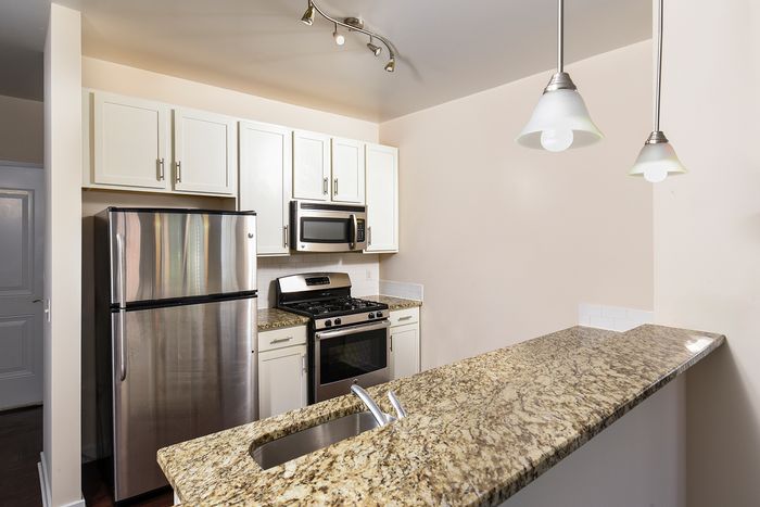 Contemporary kitchen with stainless steel appliances, elegant granite countertops, and modern lighting.