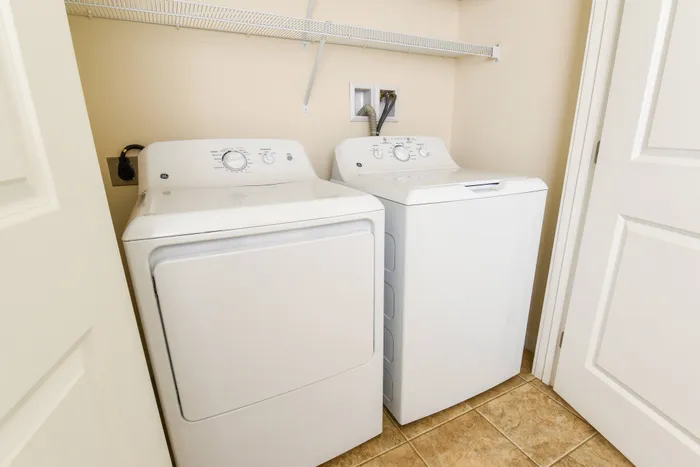 Chic laundry room with modern washer and dryer, featuring convenient shelving and elegant tile flooring.
