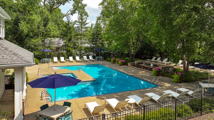 Inviting outdoor pool area surrounded by lush greenery, featuring sun loungers, vibrant flowers, and shaded seating for relaxation.