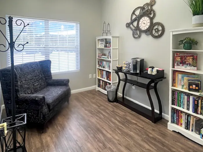 Charming reading nook featuring a cozy armchair, expansive bookshelves, and a coffee station beneath a unique gear clock.