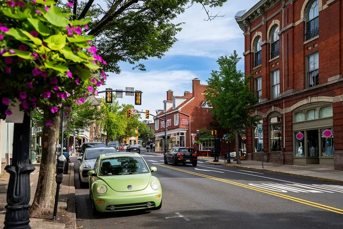 Charming urban street scene with vibrant brick buildings, lush greenery, and colorful flowers, perfect for a lively and picturesque neighborhood vibe.