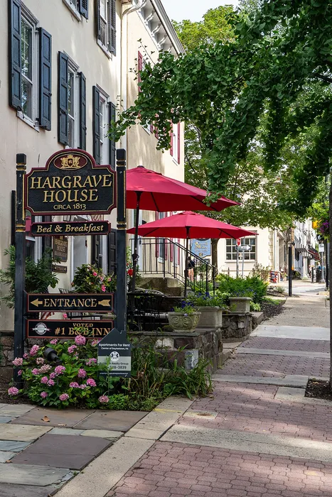 Charming Hargrave House Bed & Breakfast with vibrant red umbrellas, lush greenery, and elegant historical architecture in a picturesque setting.