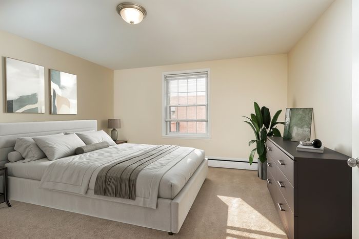 Bright and inviting bedroom featuring a plush bed, modern dresser, and natural light streaming through the window.