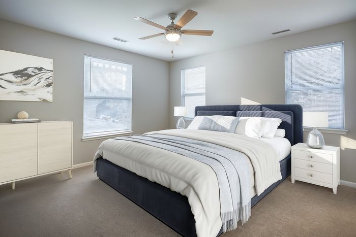 Inviting bedroom with large windows, elegant decor, and plush bedding, showcasing a serene and bright living space.