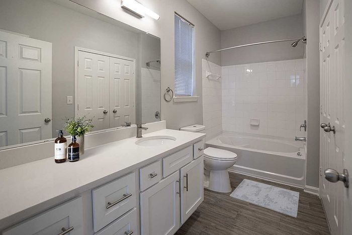 Modern bathroom with elegant white cabinetry, spacious countertop, and sleek bathtub offering a serene and chic atmosphere.