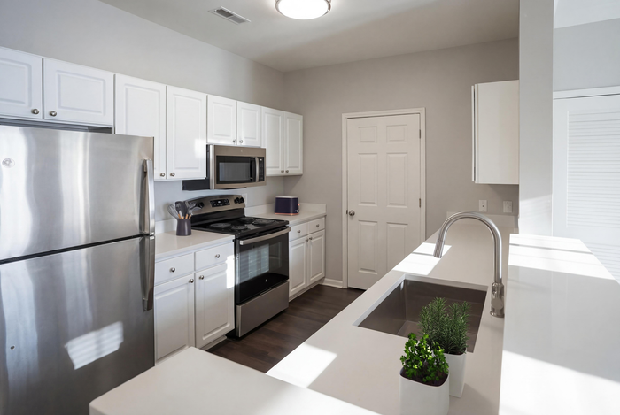 Modern kitchen with sleek stainless steel appliances, white cabinetry, and bright lighting offering a spacious and inviting atmosphere.