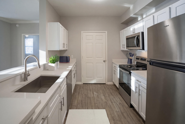 Modern kitchen with sleek stainless steel appliances, elegant white cabinetry, and stylish hardwood flooring.