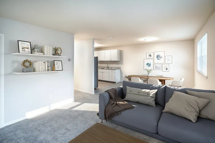 Modern and inviting open-concept living room with plush grey sofa, elegant dining area, and sleek kitchen featuring bright decor and stylish shelving.