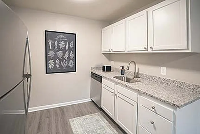 Modern kitchen with sleek granite countertops, stainless steel appliances, and ample white cabinetry.