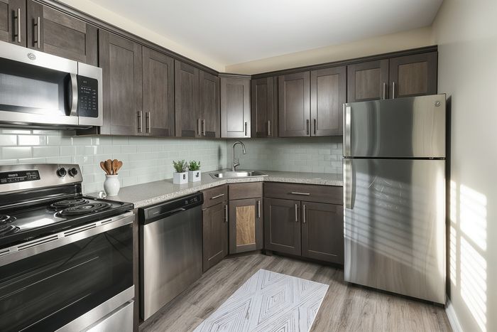 Modern kitchen with sleek stainless steel appliances, dark wood cabinetry, and natural light enhancing the chic tile backsplash.
