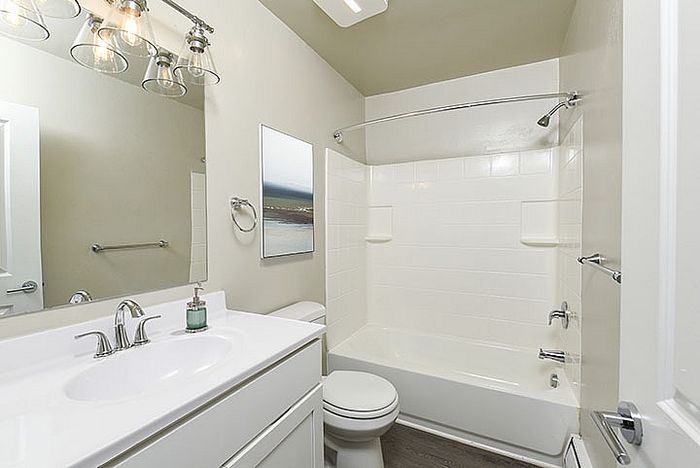 Bright, modern bathroom with white cabinetry, elegant lighting fixtures, and a sleek bathtub for a clean, refreshing space.