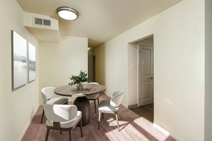 Inviting dining nook with a round wooden table and elegant seating, complemented by tasteful wall art and warm natural light.