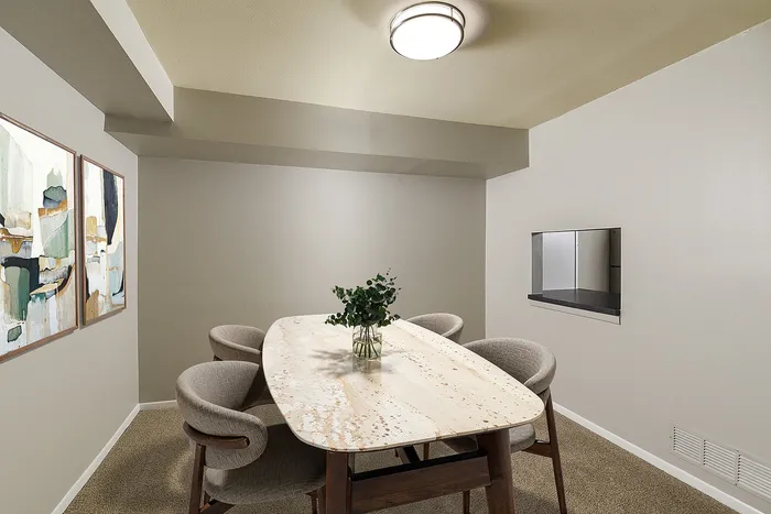 Elegant dining room with a modern oval table, stylish cushioned chairs, and contemporary artwork on soft gray walls.
