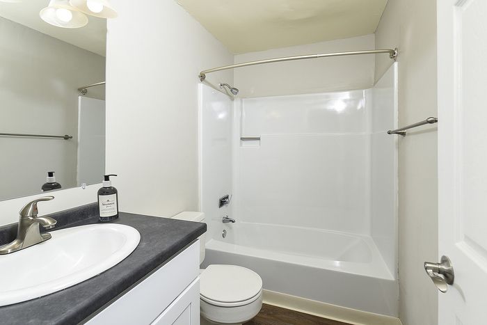 Modern bathroom with sleek fixtures, featuring a polished countertop, spacious bathtub, and contemporary lighting.