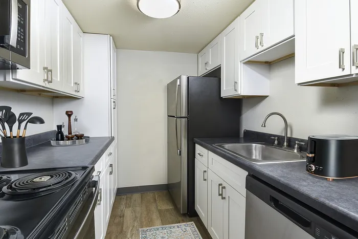 Modern kitchen with sleek black countertops, stainless steel appliances, and elegant white cabinetry.