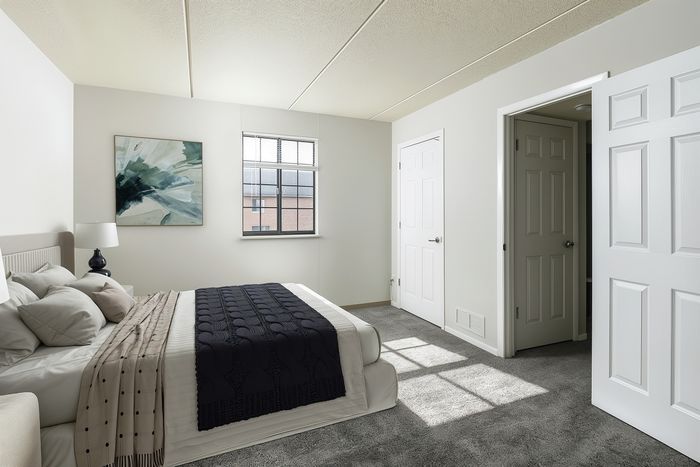 Elegant bedroom with natural light, cozy bed, stylish artwork, and modern decor in chic apartment setting.
