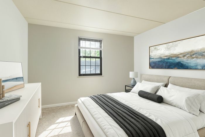 Cozy bedroom featuring a plush bed with elegant decor, large window allowing natural light, and modern artwork enhancing the serene ambiance.