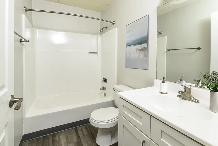 Bright modern bathroom with sleek white fixtures, elegant vanity, and soothing wall art, creating a serene oasis.