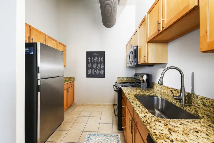 Modern kitchen with stainless steel appliances, sleek granite countertops, and stylish wooden cabinetry.