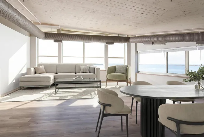 Bright, modern living area with panoramic ocean views, featuring plush seating, stylish dining set, and industrial-chic ceiling details.