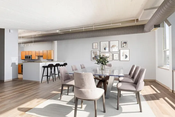 Modern open-concept dining area with elegant pastel chairs and a sleek glass table, complemented by a stylish kitchen and artistic wall decor.