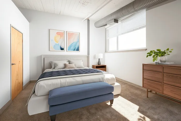 Bright and airy bedroom with modern decor, featuring a plush bed, chic artwork, and natural light streaming through large windows.