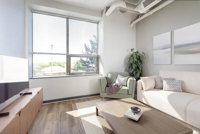 Bright and modern living room with large windows, cozy seating, and stylish decor, perfect for relaxation.