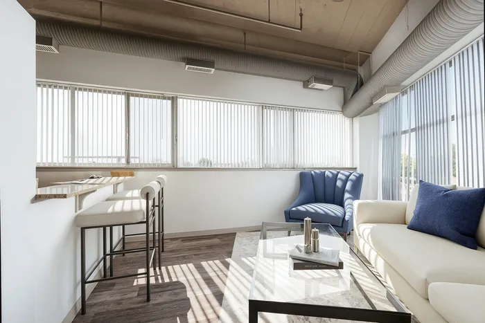 Bright and modern living room with floor-to-ceiling windows, featuring elegant furniture and sleek decor for a sophisticated ambiance.