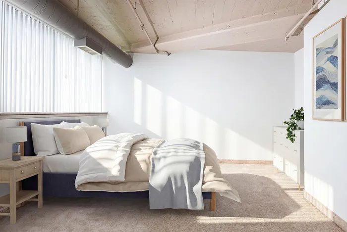 Bright and airy bedroom featuring a cozy bed with plush linens, large window with vertical blinds, and sleek modern decor.
