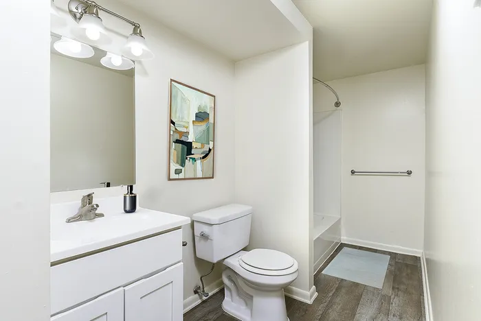 Elegant bathroom featuring modern fixtures, sleek vanity, and contemporary art on crisp white walls.