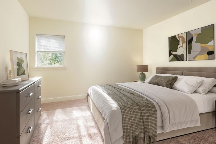 Bright and inviting bedroom featuring a plush bed, chic abstract artwork, and a window with a tranquil garden view.