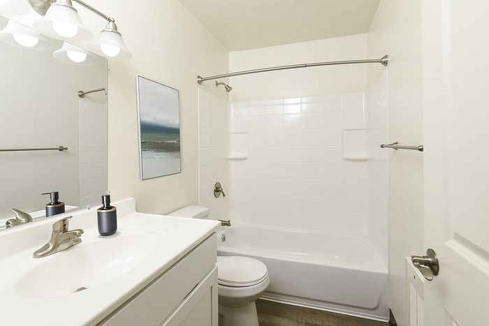 Charming bathroom with sleek white cabinetry, elegant fixtures, and a refreshing bathtub, perfect for relaxation.