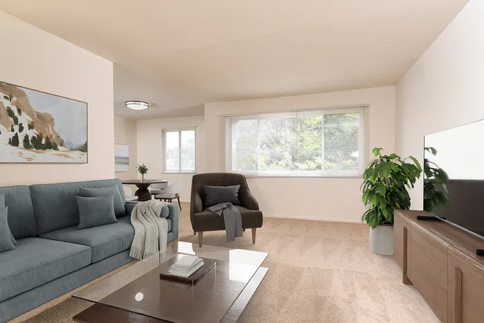 Bright, inviting living room with chic decor, featuring a cozy blue sofa, stylish armchair, and a modern entertainment unit. Large windows allow natural light to enhance the elegant ambiance.