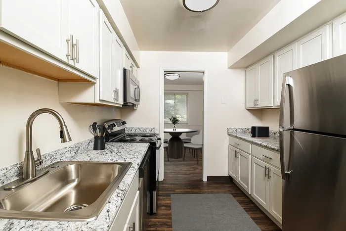 Modern kitchen with elegant granite countertops, sleek stainless steel appliances, and ample cabinet space overlooking a sunlit dining area.