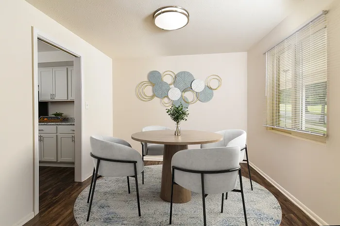Chic dining area in modern apartment featuring elegant round table, stylish gray chairs, and artistic wall decor, creating a welcoming ambiance.