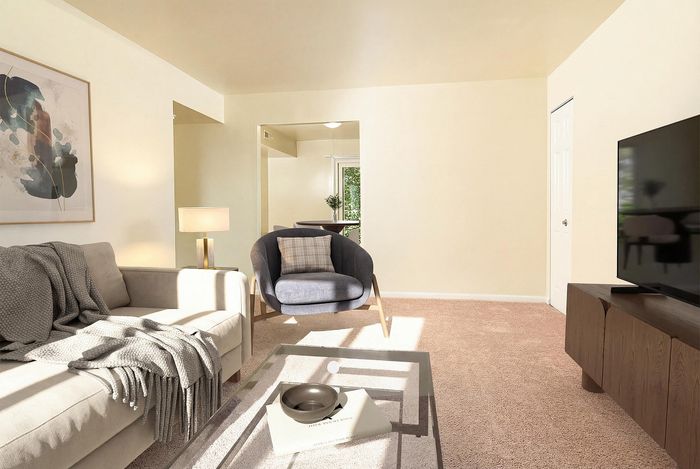 Inviting living room with cozy beige sofa, elegant armchair, and sleek glass coffee table. Warm lighting accentuates the neutral-toned decor, creating a peaceful and modern atmosphere.