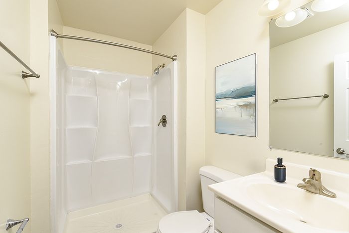 Bright and modern bathroom with a pristine white shower, elegant wall art, and stylish fixtures.