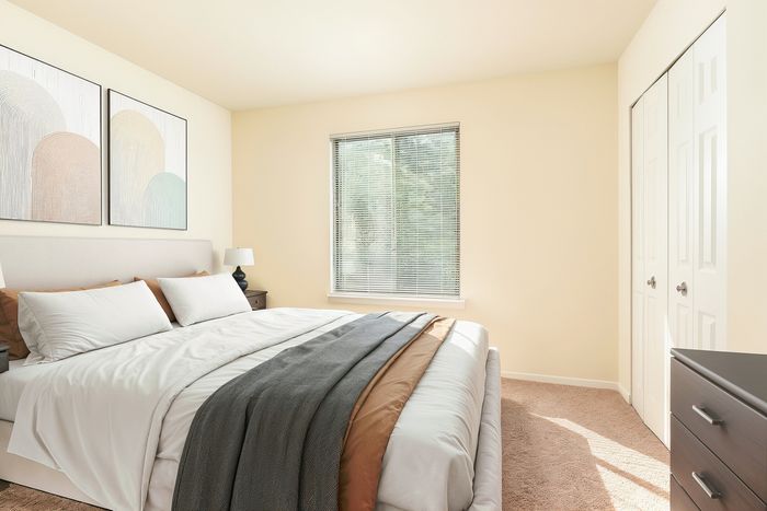 Bright and airy bedroom with a cozy bed, modern artwork, and natural light streaming through the window.