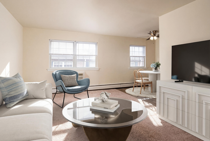 Bright and inviting living room featuring a stylish blue accent chair, modern coffee table, and cozy dining nook, perfect for relaxed living.