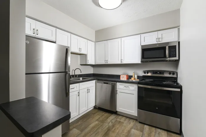 Modern kitchen with sleek stainless steel appliances, elegant white cabinetry, and stylish gray countertops.