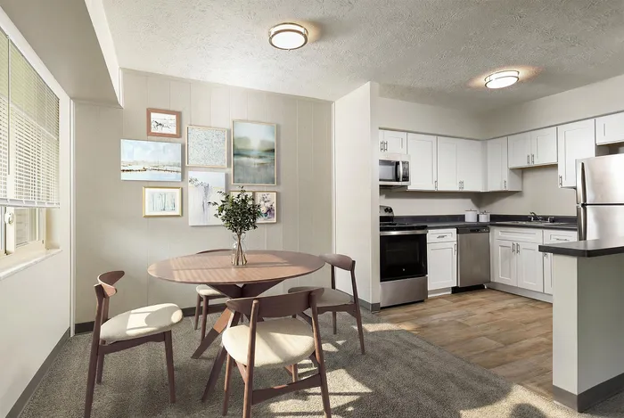 Sunlit dining area with elegant round table and modern kitchen featuring stainless steel appliances and white cabinetry.