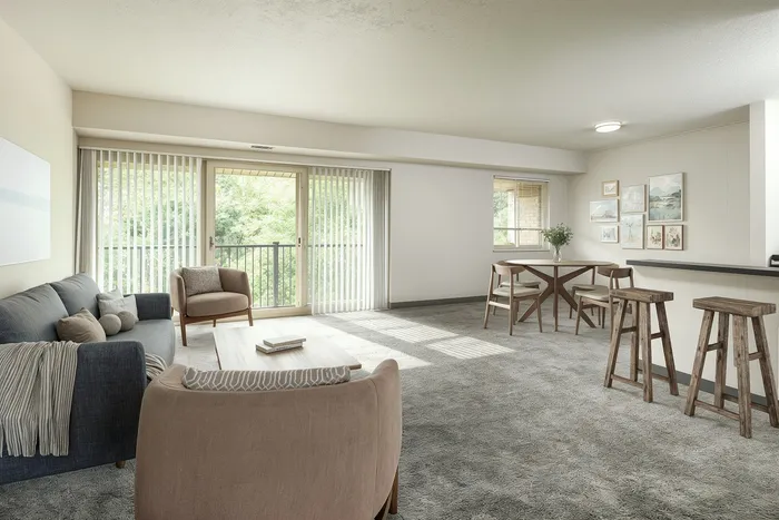 Bright and inviting living room with plush seating, chic decor, and large windows offering lush green views.