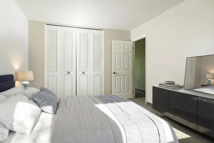 Elegant bedroom featuring a plush bed with designer pillows, soft lighting, and spacious closet doors, offering a cozy retreat.