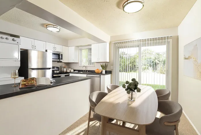 Bright and modern kitchen with sleek appliances, spacious countertops, and dining area overlooking lush garden views.