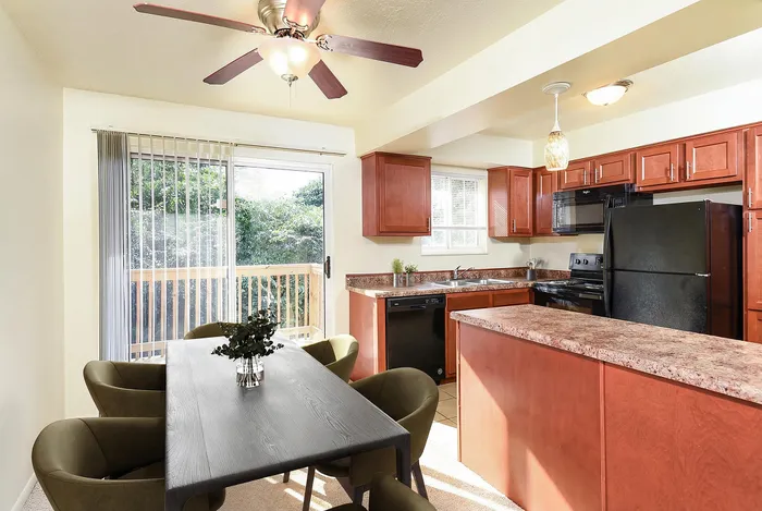 Bright and inviting kitchen with cherry cabinets, modern appliances, and a cozy dining area overlooking a lush garden view.