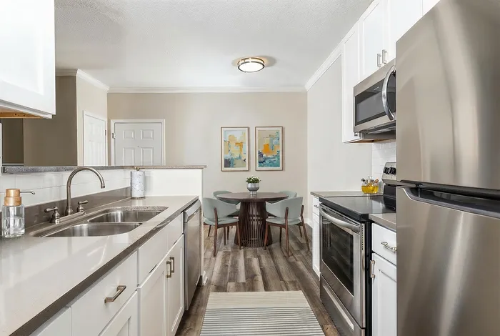 Modern kitchen with stainless steel appliances, sleek countertops, and an elegant dining area featuring stylish decor and contemporary artwork.