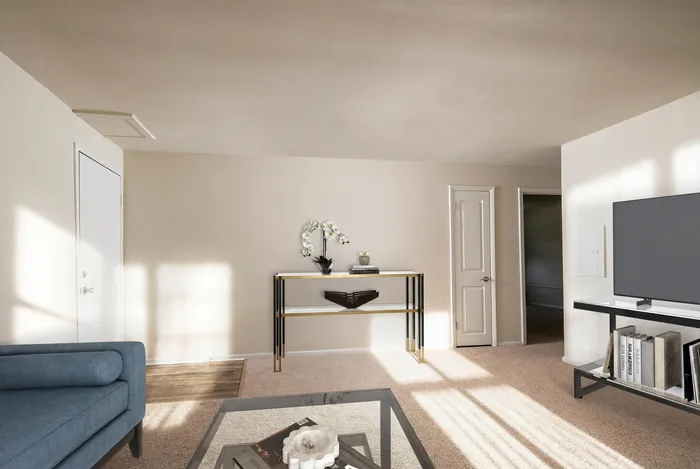 Inviting living room filled with natural light, featuring a chic blue sofa, modern glass coffee table, and a sleek console table adorned with elegant decor.