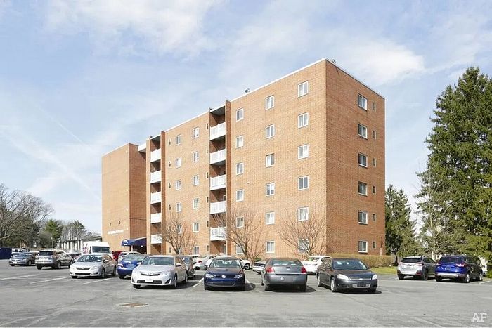 Charming brick apartment complex with ample parking space, surrounded by lush greenery and a serene atmosphere.
