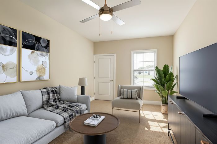 Inviting living room with modern design, featuring a plush gray sofa, elegant armchair, and stylish decor, with natural light streaming through a large window.