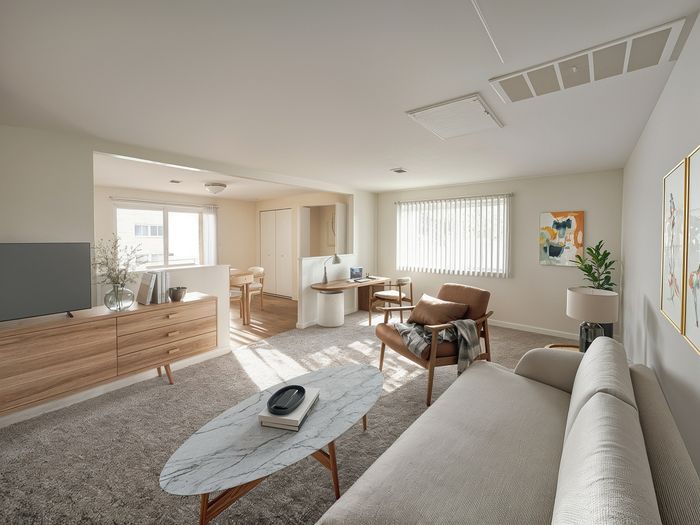 Elegant living room with modern furniture, plush carpeting, and abundant natural light, flowing into a cozy dining area.